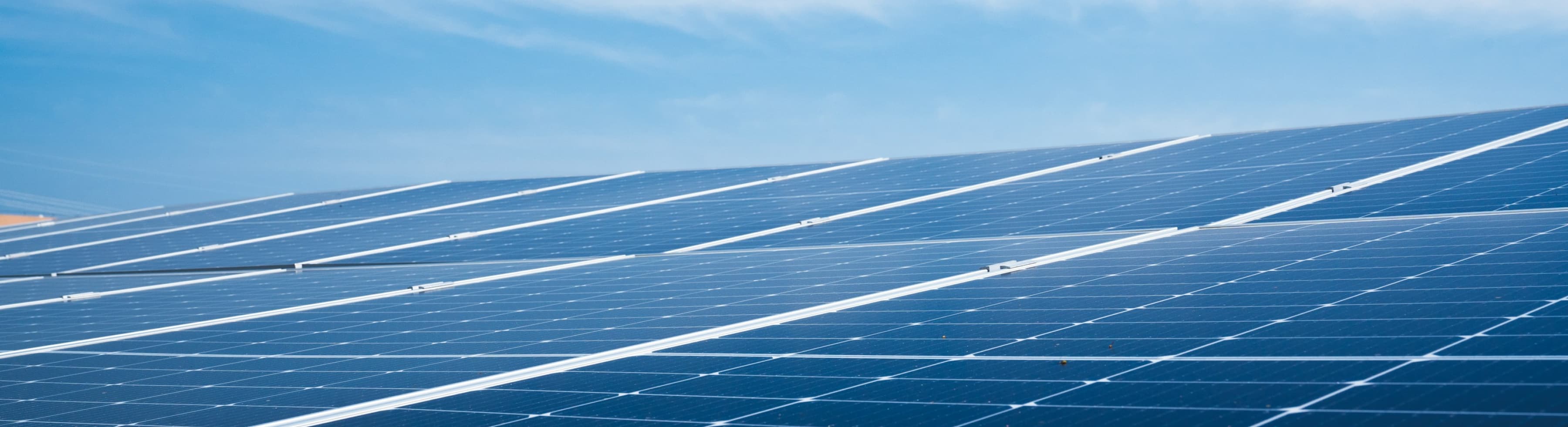 Rows of solar panels are installed outdoors under a clear blue sky.